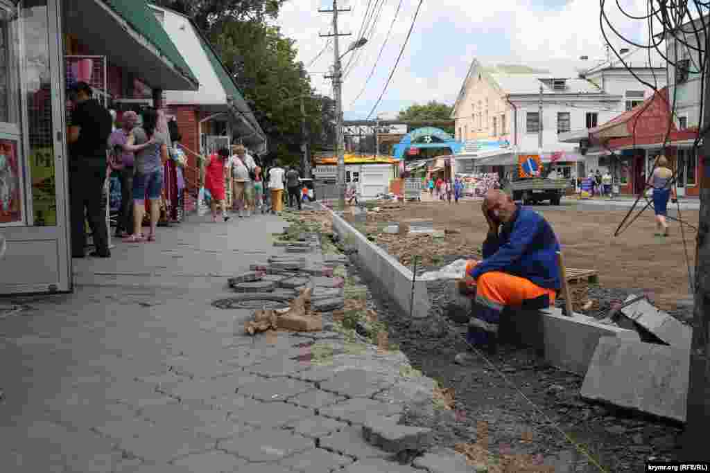 Часть деревьев, которые мешали расширению улицы, спилили. Рабочие старательно укладывает новый бордюр, 16 июля 2015 года