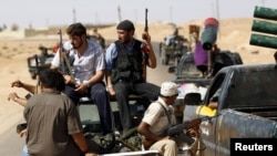 Rebel fighters patrol the town of Abu Grein, some 128 kilometers west of Sirte, on August 29.
