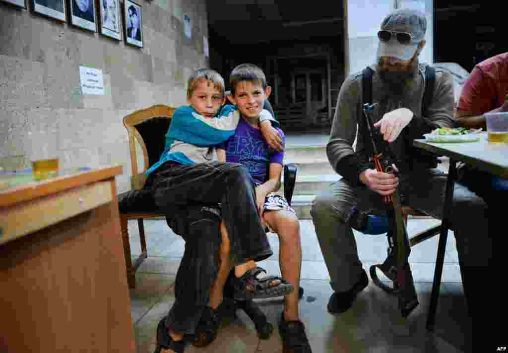 Хлопчики фотографуються поруч з озброєним бойовиком у штаб-квартирі угруповання «ДНР» в Донецьку, 12 червня 2014 року