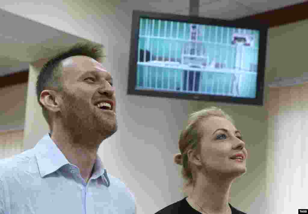 Алексей Навальный и его супруга Юлия во время слушаний по апелляции на приговор по делу "Ив Роше".  На экране - брат Алексея Олег, который приговорен к реальному сроку. 17 февраля 2015 года. 