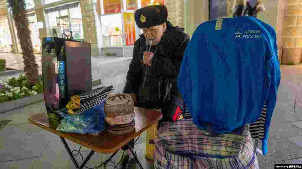 А пенсионер в норковой шапке с военно-морской кокардой поет как умеет советские песни и заодно продает морские пилотки 