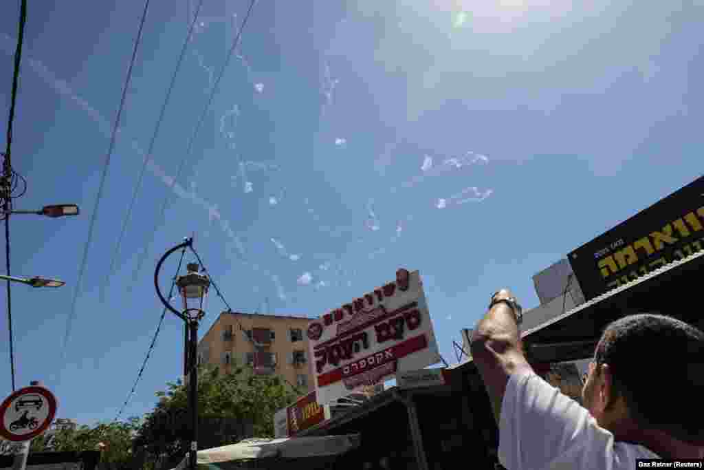 Чоловік ховається біля свого авта, коли сирена попереджає про наближення ракет, запущених зі Смуги Гази в напрямку Ізраїлю, а ізраїльська протиракетна система «Залізний купол» перехоплює ракети, запущені зі Смуги Гази, неподалік від Ашкелона. Ізраїль, 19 травня 2021 року 