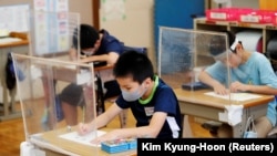 У Японії власна система: шкільний рік закінчується в кінці березня, а новий починається вже через тиждень, на початку квітня, але є довші літні канікули в серпні і зимові наприкінці грудня – на початку січня. На фото: початкова школа, з масками і захисними щитками, в місті Фунабасі, Японія, 16 липня 2020 року