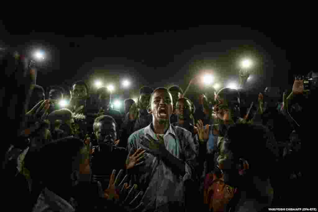 Молодий чоловік освітлений мобільними телефонами декламує протестну поезію, в той час як демонстранти скандують гасла. Хартумі, Судан, 19 червня 2019 року. Фото року World Press Photo: Переможець – Ясуйоші Чіба, Агенція «Франс-Прес»