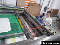 Наталія наносить фарбу на матеріал під час роботи у друкарні