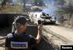 Один із членів місії ОБСЄ спостерігає за відведенням української бронетехніки на лінії зіткнення сторін у Луганській області