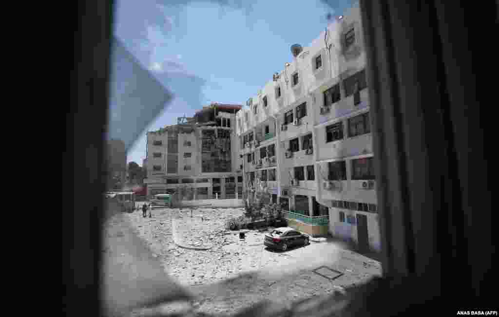 Через розбите вікно видно будівлю міністерства охорони здоров'я Палестини в Газі, яка була сильно пошкоджена внаслідок ізраїльських бомбардувань міста. Фото від 19 травня