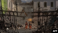 Українські рятувальники біля завалів будинку внаслідок ракетного обстрілу в Сумах, 14 квітня 2025 року.