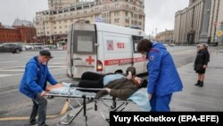 Росія: лікарі забирають жінку до карети швидкої допомоги. 17 квітня 2020 року.