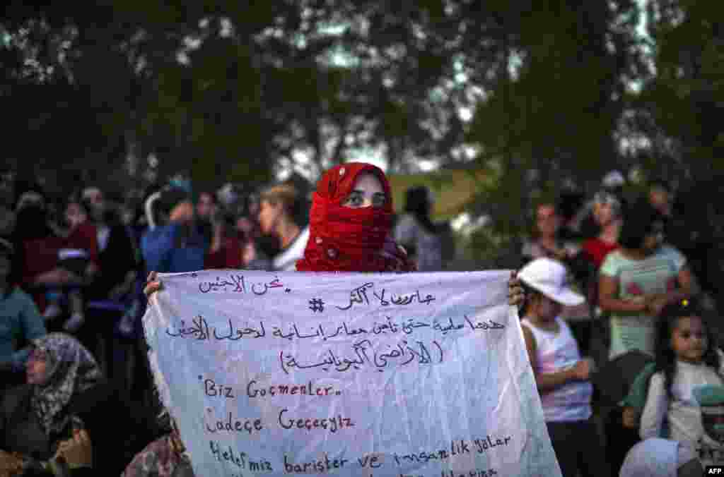 Сирийская женщина на сухопутной границе Турции и Греции держит в руках плакат с надписью: "Мы беженцы! Мы все равно пройдем в Европу". 17 сентября