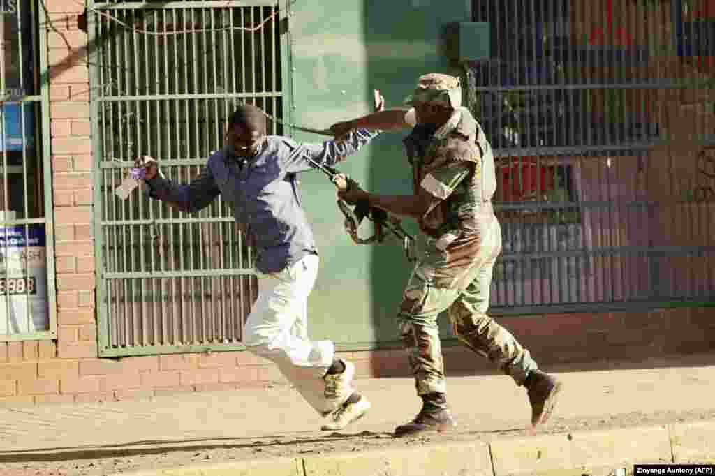 Зимбабвийский солдат бьет мужчину на улице в Хараре после того, как вспыхнули протесты из-за предполагаемого мошенничества на всеобщих выборах в стране. (AFP/Zinyange Auntony)