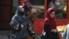Afghan women walk past a Taliban fighter on the streets of Kabul.