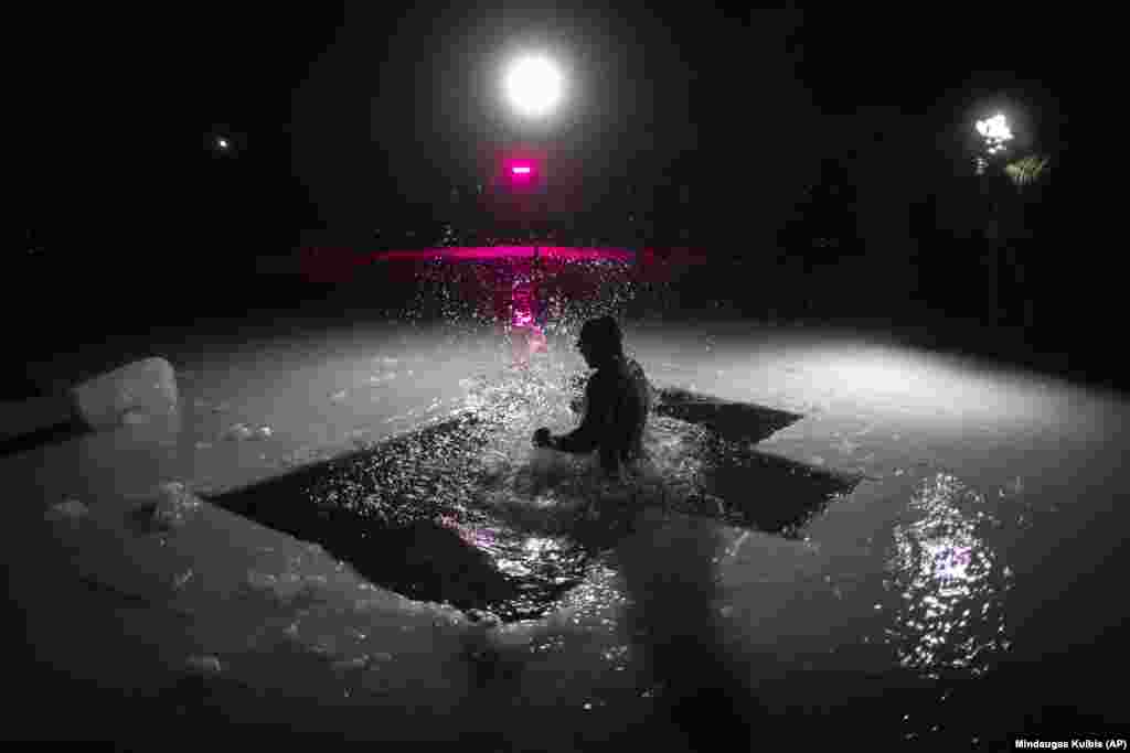 Литовський православний купається у крижаній воді невдовзі після півночі в озері неподалік литовської столиці Вільнюса