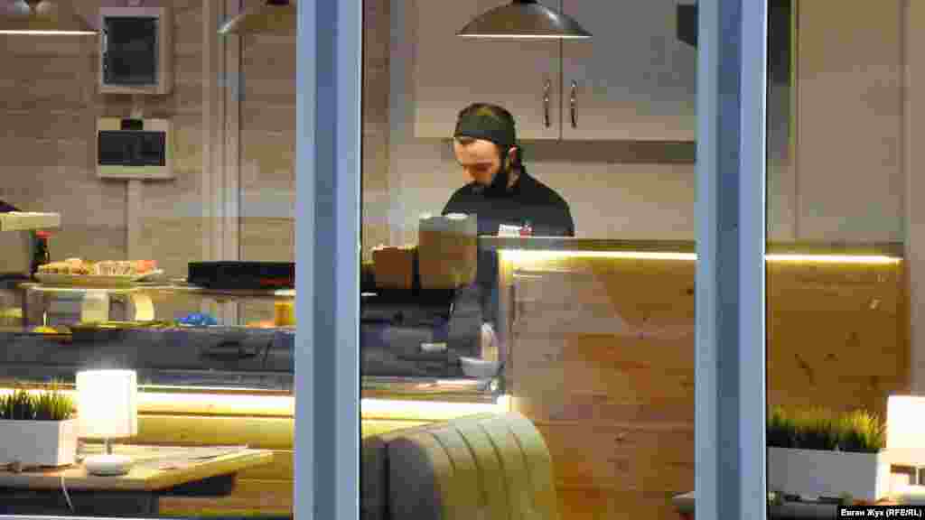 Продавец упаковывает суши, маска – на подбородке