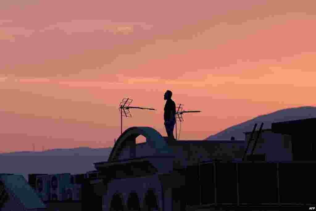 Мужчина стоит на крыше здания, наблюдая за горизонтом в Тегеране 16 июня 2025 года. ATTA KENARE / AFP