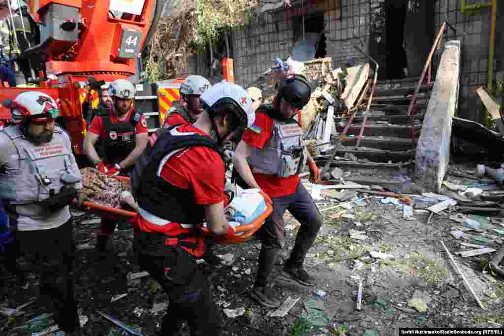 Спасатели и медики выносят раненую женщину на месте российского удара в жилой дом. Киев, 17 июня 2025 года