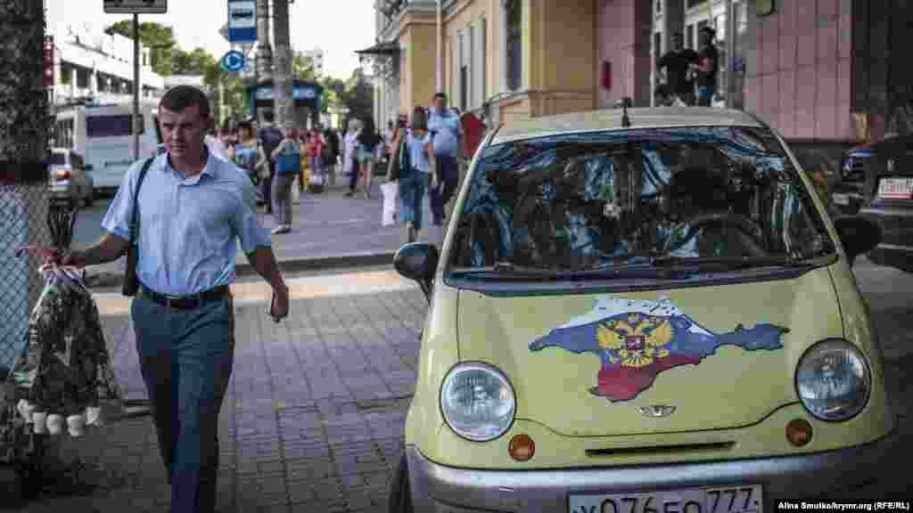 Мужчина с цветами проходит мимо «патриотического» автомобиля