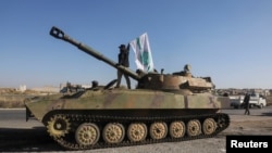 Боєць повстанської армії стоїть на військовій машині з прапором угруповання «Гаят Тахрір аш-Шам» у Саракебі