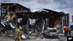 Українські військовослужбовці проходять повз будівлю, пошкоджену російською атакою в Дніпрі, Україна, 19 квітня 2024 року