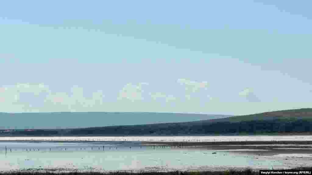 Соленые воды озера Чокрак ежегодно приманивают сотни туристов, желающих набрать местной грязи. Сейчас здесь пустынно. Ряды деревянных кольев, которые виднеются в воде – это остатки соляных чеков, на которых в конце XIX века добывали соль