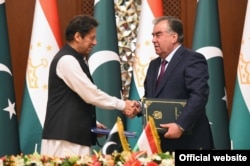 Pakistani Prime Minister Imran Khan (left) and Tajik President Emomali Rahmon shake hands at their meeting in Dushanbe on September 17.