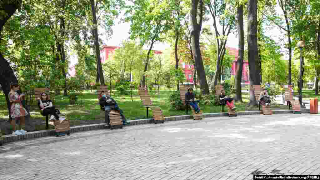 Киевляне на лавочках в парке имени Тараса Шевченко. На фоне – главный (красный) корпус Национального университета имени Шевченко