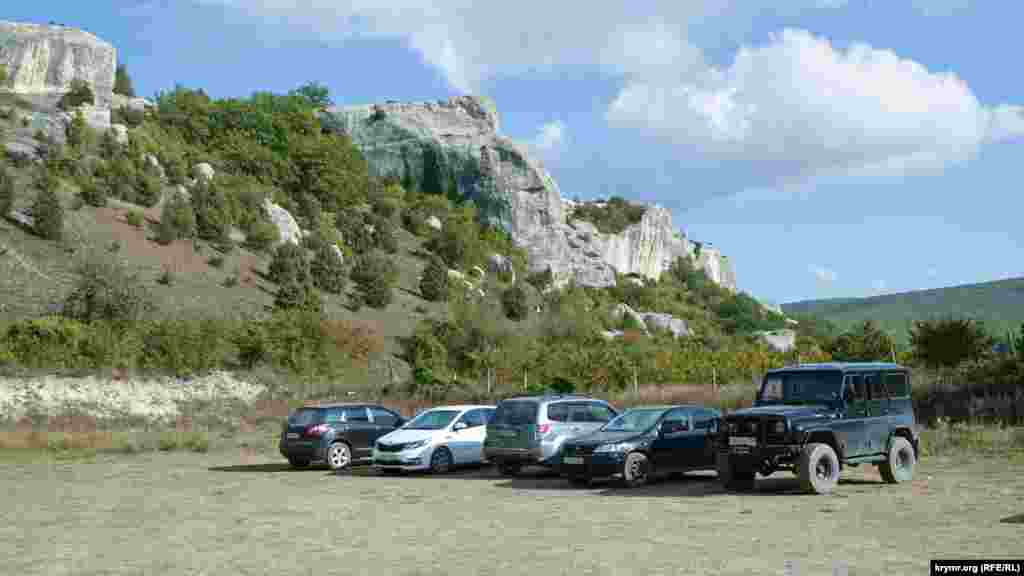 У подножия скал паркуются автомобили отдыхающих. Доехать сюда можно не только на личном транспорте: из Бахчисарая и Севастополя сюда ходят автобусы  