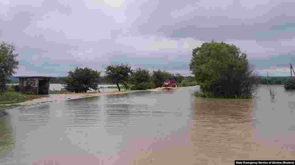 Пожежне авто їде затопленою дорогою біля села Мельнич Жидачівського району на Львівщині, 24 червня