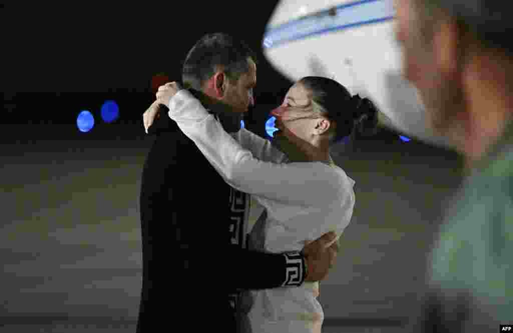 Американо-российская балерина Ксения Карелина обнимает своего бойфренда, южноафриканского боксёра Криса ван Хердена, по прибытии на базу Эндрюс в Мэриленде после своего освобождения из России. Она была заключена под стражу за пожертвование в размере 51 доллара украинской благотворительной организации, базирующейся в США, и была освобождена в рамках обмена заключёнными. ROBERTO SCHMIDT / AFP