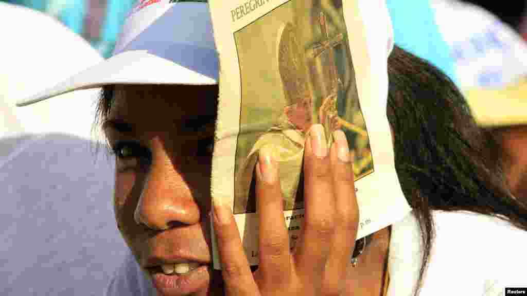 Женщина прикрывает лицо от солнца, ожидая выступления Папы Бенедикта XVI   на площади Антонио Масео, Сантьяго-де-Куба