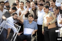 Mir, in a wheelchair, leaves after appearing before a judicial commission that is investigating an attack against him in 2014.