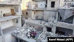 Сирійська родина на руїнах своєї оселі в місті Аріха, провінція Ідліб