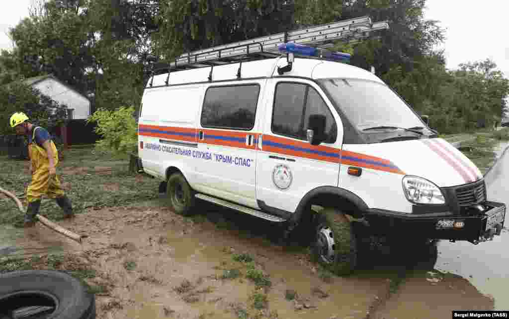 Сотрудник «Крым-Спас» откачивает воду из двора затопленного дома