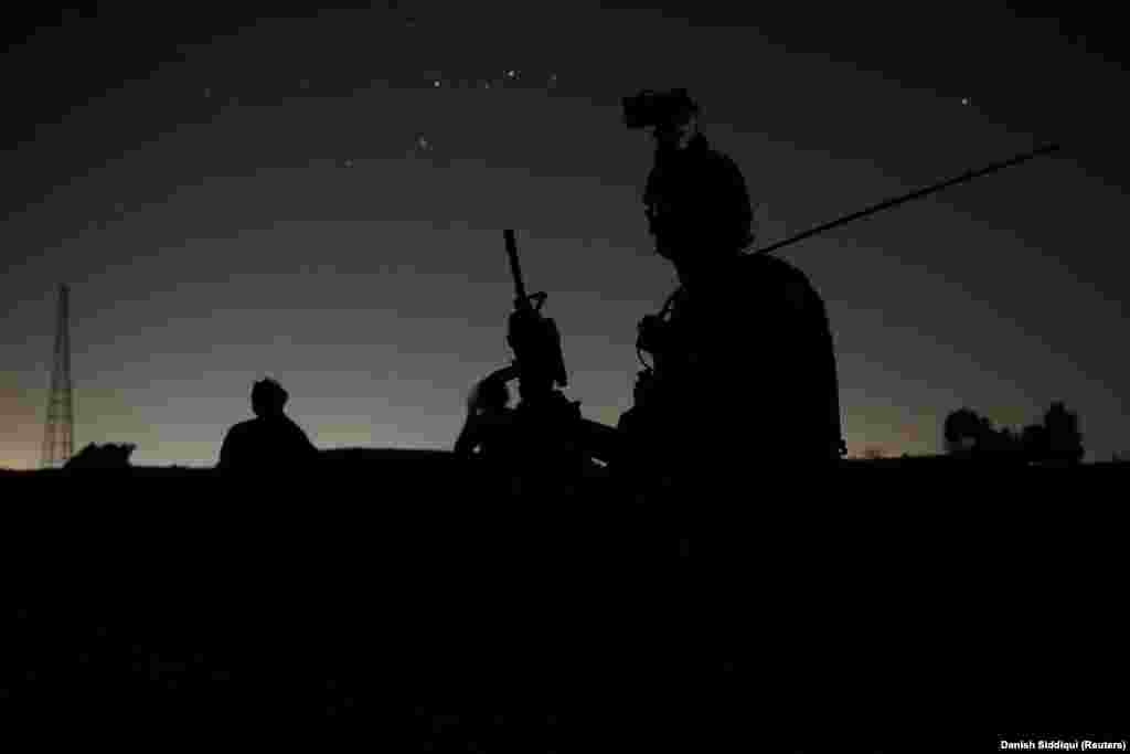 Members of the Afghan special forces keep watch as comrades search houses during the nighttime mission in Kandahar. Taliban spokesmen claim the Islamic extremist group has taken control of 85 percent of Afghanistan's territory, an assertion that was dismissed by Afghan officials as propaganda.