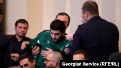 პენიტენციური სამსახურის თანამშრომლები რეზო კიკნაძეს სხდომათა დარბაზიდან აძევებენ.