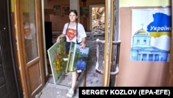 Місцева дівчина виносить картини з будинку культури в місті Чугуєві, який постраждав від обстрілу російських військових. Чугуїв, Харківщина, 25 липня 2022 року