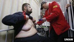 Лікар «швидкої допомоги» оглядає народного депутата України від Радикальної партії Ігоря Мосійчука, звинуваченого в корупції. Зал засідань Апеляційного суду Києва, 8 жовтня 2015 року