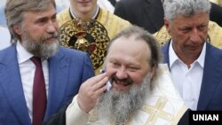 Народні депутати від «Опозиційного блоку» Вадим Новинський (ліворуч) і Юрій Бойко (праворуч) та намісник Києво-Печерської лаври митрополит УПЦ (Московського патріархату) Павло (Лебідь). Київ, 27 липня 2017 року