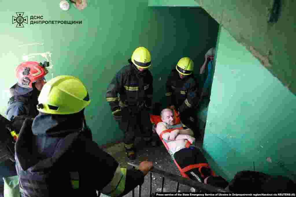 Рятувальники несуть пораненого чоловіка з житлового будинку, пошкодженого російським ракетним ударом, Дніпропетровщина, 24 червня 2025 року