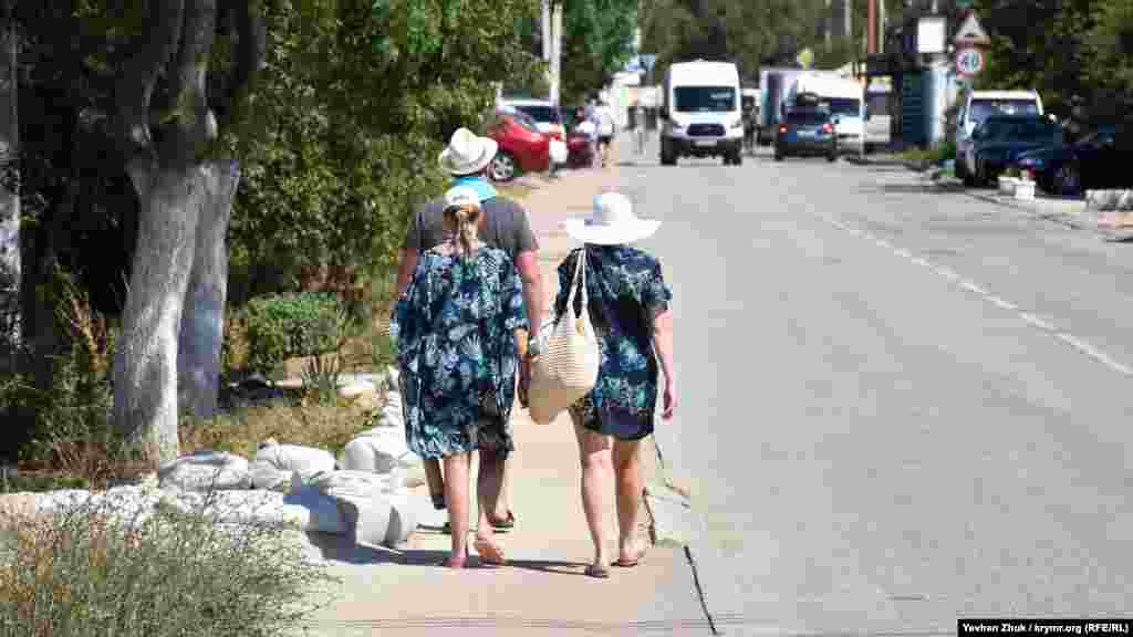 Отдыхающие идут с пляжа по одной из главных улиц в Любимовке – Южногородской