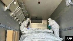 Представники Міжнародного комітету Червоного Хреста перевіряють мішки з останками військовослужбовців під час обміну тілами, серпень 2024 року