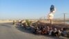 Afghan border guards who fled to Tajikistan after a Taliban attack sit on the side of the road on June 22.