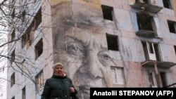 Марина Марченко на тлі муралу з її портретом в Авдіївці