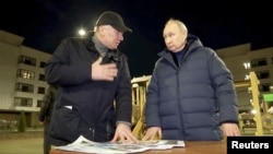 Путін уночі (або, як пишуть деякі ЗМІ - його двійник) в окупованому Маріуполі , уночі, розглядає «плани відбудови» майже повністю зруйнованого російськими бомбардуваннями і захопленого українського міста. Звітує віце-прем’єр-міністр Росії Марат Хуснуллін. 19 березня 2023 року