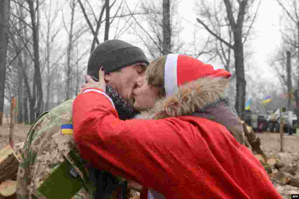 Волонтерка «Армії Допомоги» в костюмі Діда Мороза цілує військовослужбовця української армії під час новорічного вертепу на блокпосту біля міста Щастя, 28 грудня 2013 року