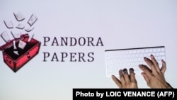 د پنډورا اسنادو انځوریزه ننداره کې یو کمپویټري کیبورډ او له یوې سرخلاصې پېټې پاڼې بادېږي