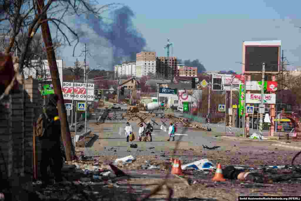 Люди пішки, прикрившивсь білим, виходять із Бучі.Ліворуч фото від 11 березня 2022, праворуч – Бберезень 2025 року