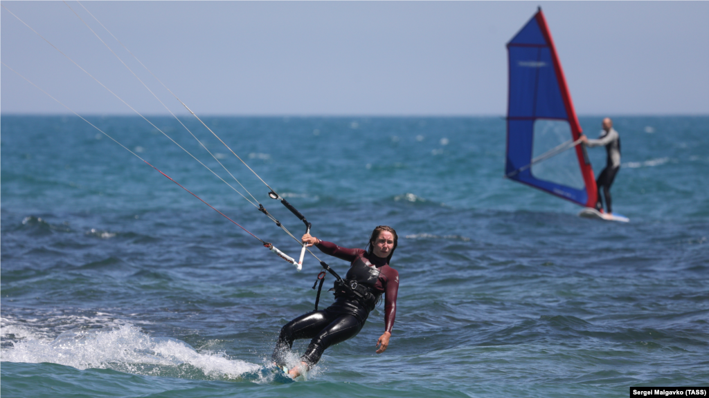 Кайтсерфер и виндсерфер держатся на волнах 