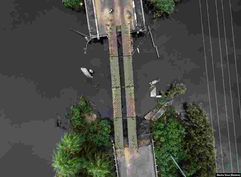 Жінка перетинає міст поблизу села Мала Рогань, 4 серпня 2022 року.   Міст був частково відновлений українськими військовими  