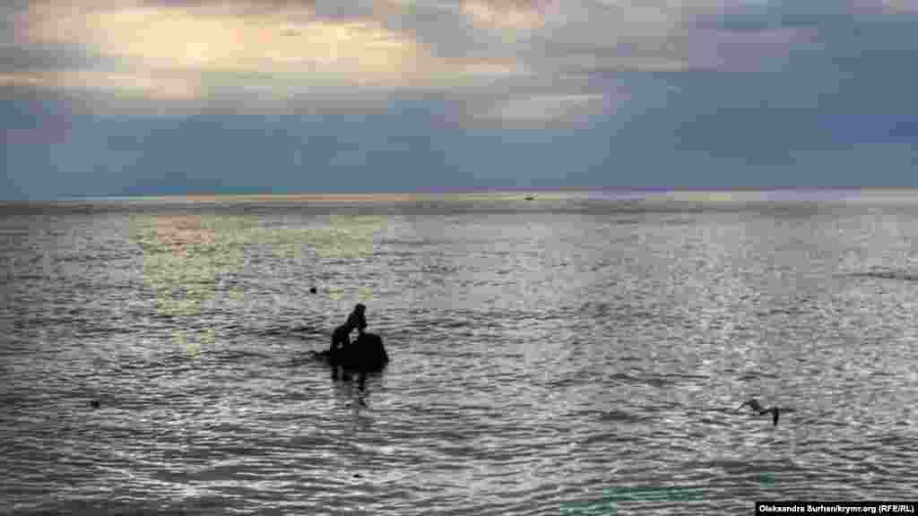 Если смотреть на скульптуру со стороны пирса, заметен ее хвост. Русалка расположена в воде таким образом, будто взгляд ее бронзовых глаз направлен на гору Ай-Петри